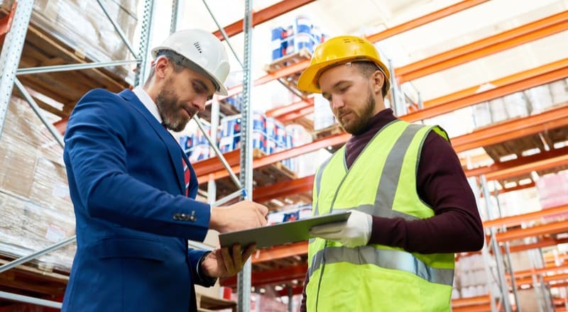 Jefe de almacén junto a trabajador calculando el Punto de Reorden.